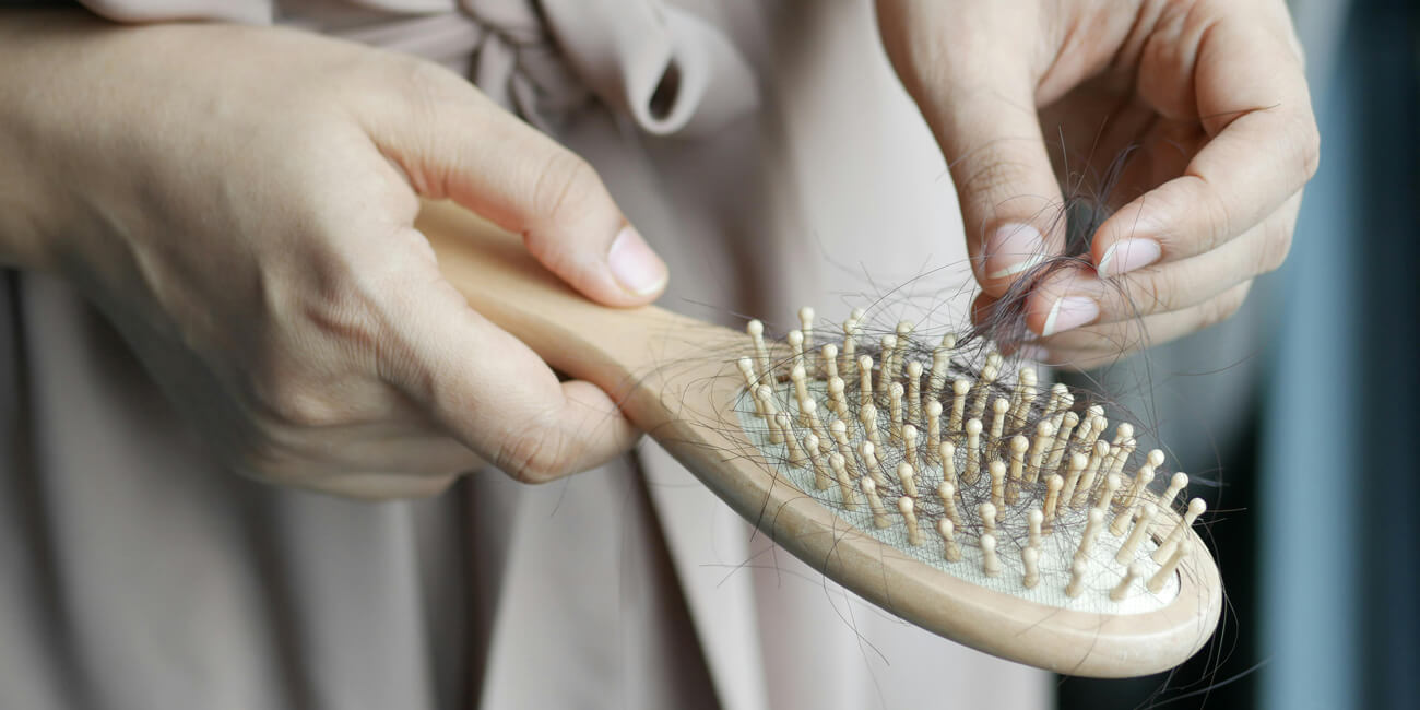 Hair loss is a hair brush held by a womans hand